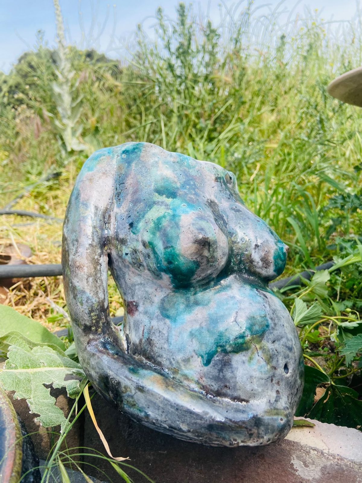Escultura de cerámica de un torso de mujer embarazada con esmalte verde y turquesa